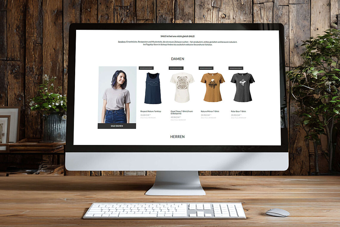 Ein Desktop-Computer zeigt die Website von WE ARE ZRCL mit einer Sale-Seite für Damenmode. Auf dem Bildschirm sind verschiedene T-Shirts und ein Tanktop mit Preisen sichtbar.